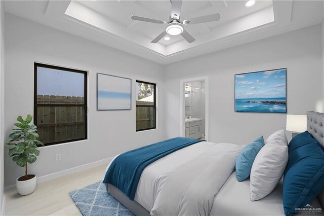 bedroom with baseboards, a tray ceiling, recessed lighting, ceiling fan, and connected bathroom