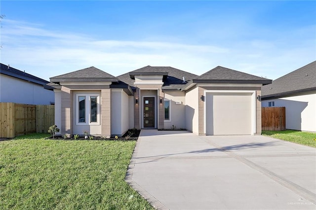 prairie-style house with fence, driveway, stucco siding, a front lawn, and a garage