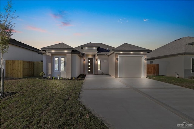 prairie-style house featuring a garage, concrete driveway, stucco siding, and fence