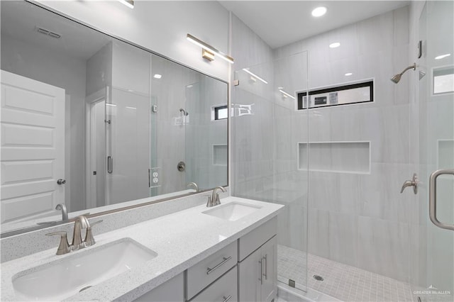 full bathroom with double vanity, a shower stall, and a sink