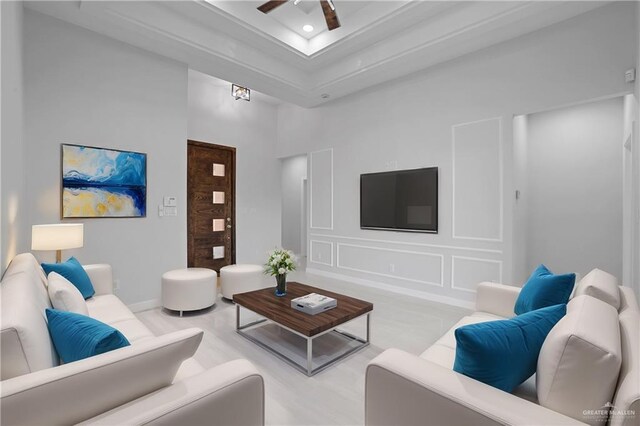 living area with a decorative wall, a high ceiling, and a ceiling fan