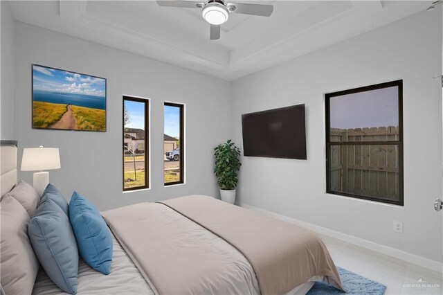 bedroom with a tray ceiling, baseboards, ceiling fan, and light tile patterned flooring