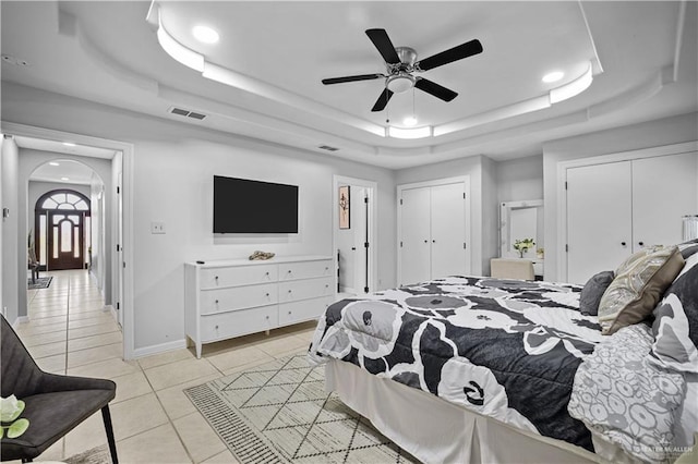 317 Ohara Dr, Pharr, TX 78577 - bedroom featuring a raised ceiling, multiple closets, arched walkways, light tile patterned floors, and recessed lighting