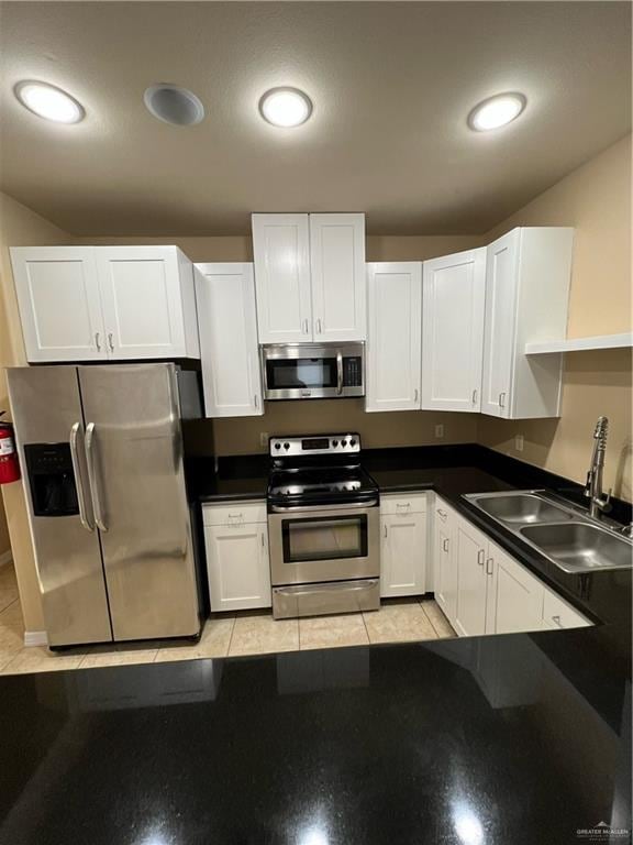 kitchen featuring sink, white cabinetry, stainless steel appliances, and light tile patterned floors