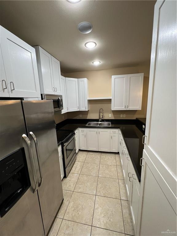 kitchen with white cabinetry, sink, light tile patterned floors, and appliances with stainless steel finishes