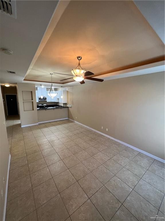 unfurnished living room featuring ceiling fan, a raised ceiling, and light tile patterned floors