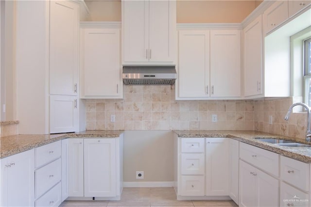 kitchen featuring light stone counters, sink, and white cabinets