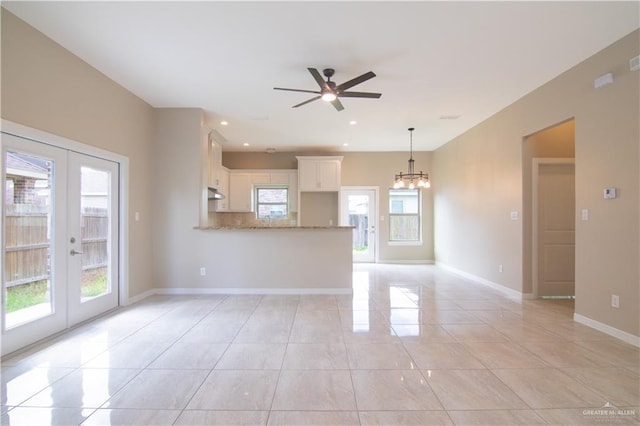 unfurnished living room with french doors, ceiling fan with notable chandelier, and light tile patterned floors