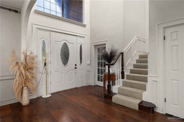 entryway with a towering ceiling and dark wood-type flooring