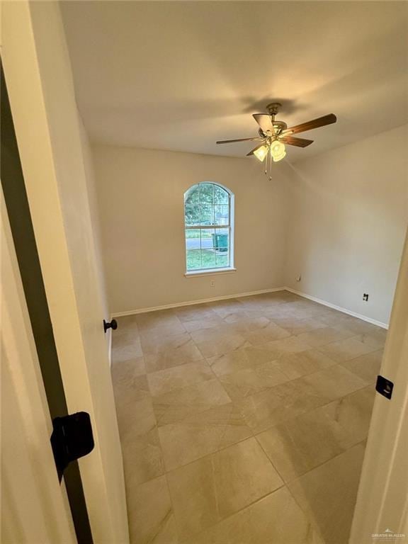 spare room with a ceiling fan, baseboards, and light tile patterned flooring