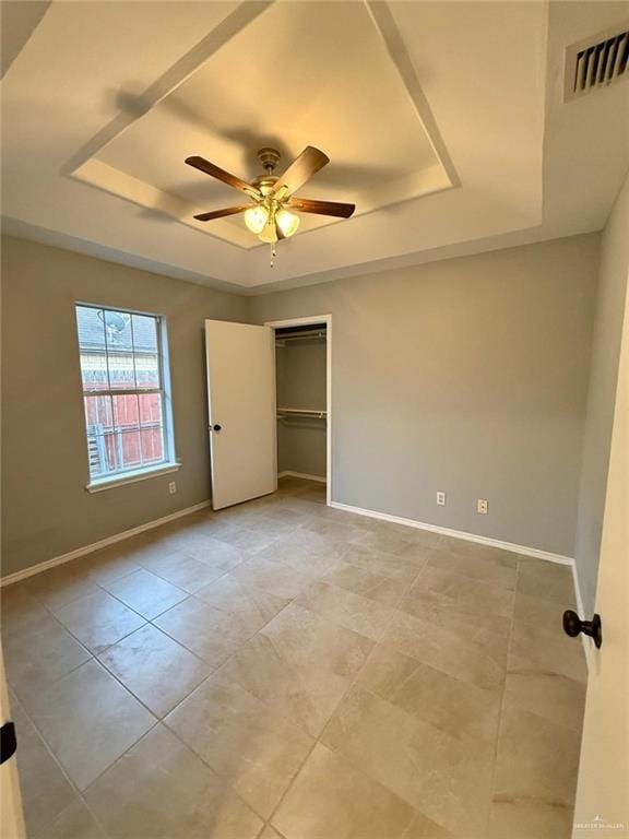 unfurnished bedroom with visible vents, baseboards, a tray ceiling, and a closet
