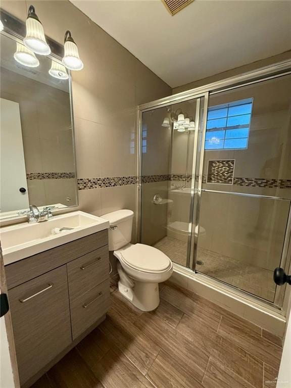full bathroom with wood finished floors, visible vents, toilet, vanity, and a stall shower