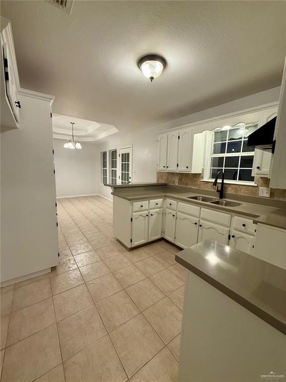 kitchen with white cabinets, light tile patterned floors, a sink, decorative backsplash, and a peninsula
