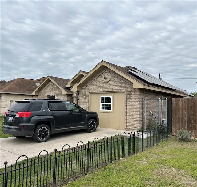8601 Las Palmas Dr, Pharr, TX 78577 - view of side of home with roof mounted solar panels, an attached garage, concrete driveway, a fenced front yard, and brick siding