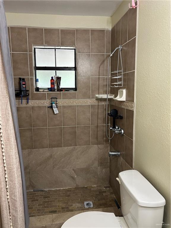 8601 Las Palmas Dr, Pharr, TX 78577 - full bathroom with toilet, a textured wall, and a tile shower