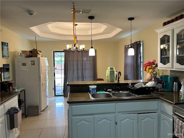 8601 Las Palmas Dr, Pharr, TX 78577 - kitchen featuring a peninsula, white cabinetry, freestanding refrigerator, dark countertops, and a raised ceiling