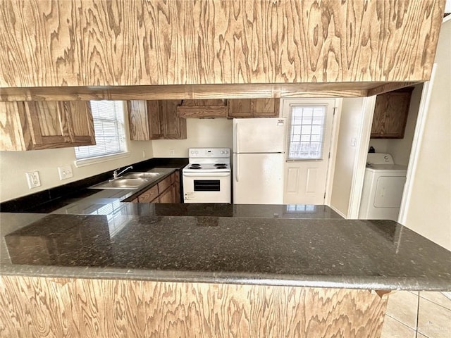 kitchen featuring white appliances, sink, light tile patterned flooring, washer / dryer, and kitchen peninsula