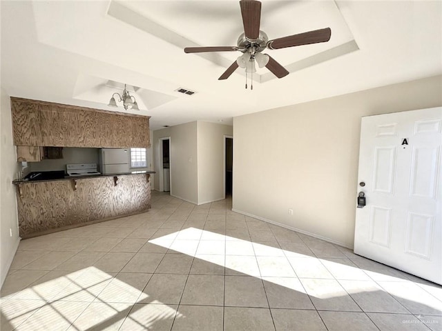 unfurnished living room with a tray ceiling, ceiling fan, and light tile patterned floors