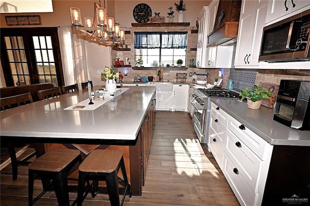 kitchen with a kitchen breakfast bar, a kitchen island with sink, white cabinetry, and appliances with stainless steel finishes