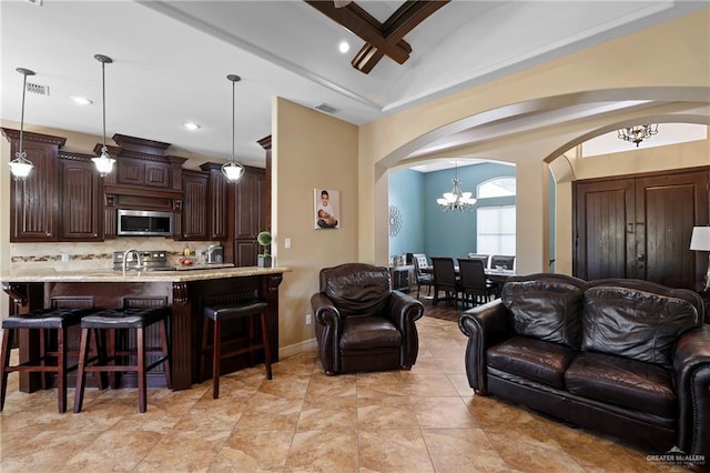 living room with arched walkways, light tile patterned floors, visible vents, baseboards, and an inviting chandelier