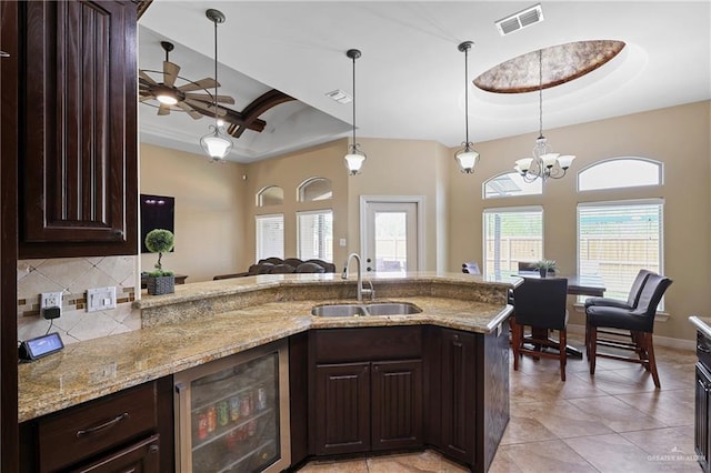 kitchen featuring beverage cooler, a raised ceiling, a sink, and visible vents