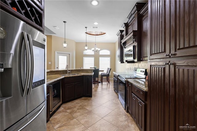 kitchen with stainless steel appliances, stone counters, a sink, and dark brown cabinets