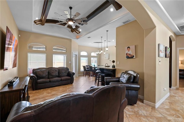 living area with arched walkways, ceiling fan, visible vents, and baseboards