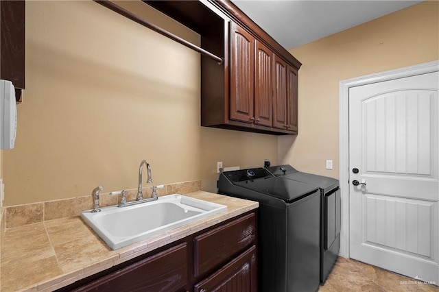 clothes washing area featuring washer and clothes dryer, a sink, and cabinet space