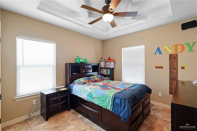 bedroom with baseboards, a tray ceiling, and a ceiling fan