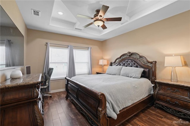 bedroom with dark wood-style floors, a tray ceiling, recessed lighting, visible vents, and baseboards