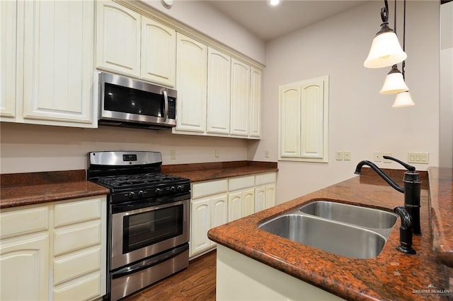 kitchen featuring sink, dark hardwood / wood-style flooring, pendant lighting, stainless steel appliances, and cream cabinetry