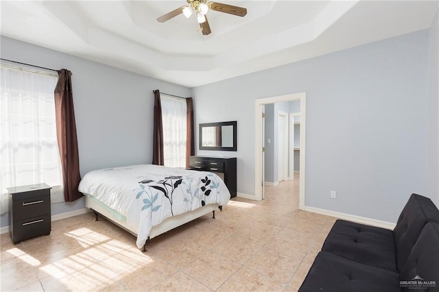 tiled bedroom featuring a tray ceiling and ceiling fan