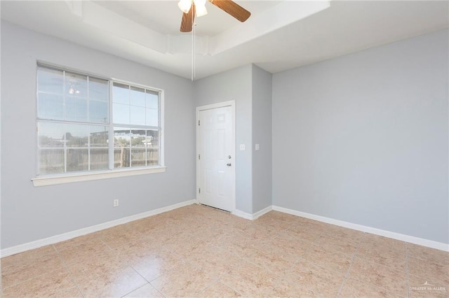 tiled spare room featuring plenty of natural light, ceiling fan, and a raised ceiling