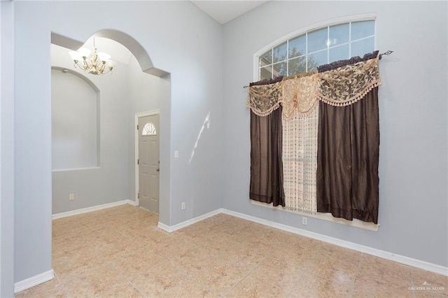 unfurnished room featuring a chandelier