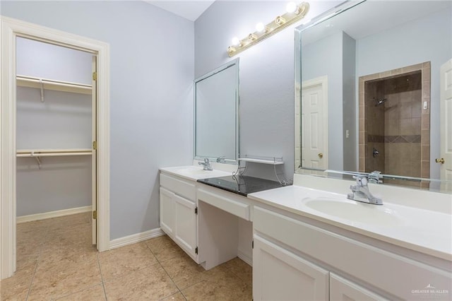 bathroom with tile patterned flooring, vanity, and tiled shower