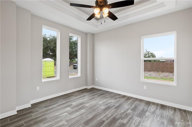 spare room with hardwood / wood-style flooring, a raised ceiling, and ceiling fan