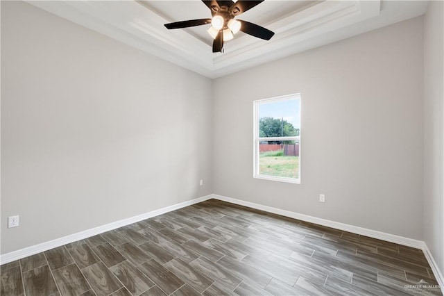 unfurnished room with dark hardwood / wood-style flooring, ceiling fan, and a raised ceiling