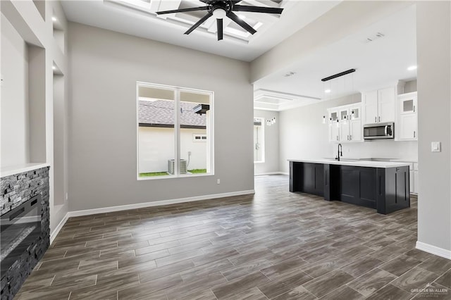 unfurnished living room featuring ceiling fan, dark hardwood / wood-style floors, sink, and a fireplace