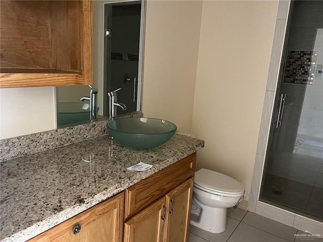 bathroom with tile patterned floors, vanity, a shower with shower door, and toilet