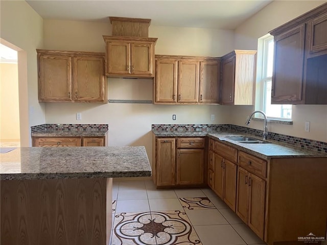 kitchen featuring backsplash, light tile patterned floors, and sink