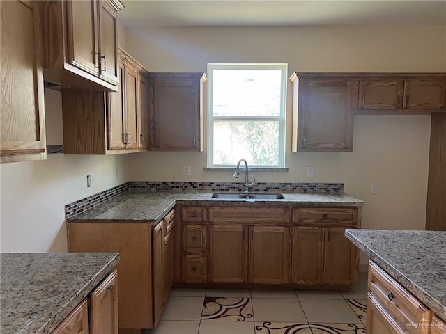 kitchen featuring tasteful backsplash, dark stone countertops, sink, and light tile patterned flooring