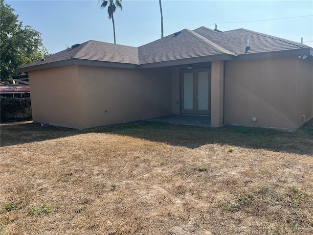 rear view of property featuring french doors and a lawn