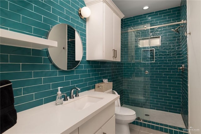 bathroom featuring tile walls, a stall shower, toilet, vanity, and tile patterned flooring