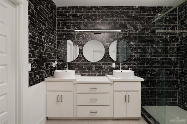 full bath with tiled shower, double vanity, and tile patterned flooring