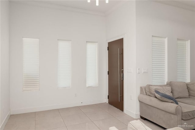living area featuring crown molding, baseboards, and light tile patterned flooring