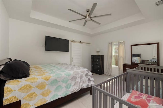 tiled bedroom with a tray ceiling and a ceiling fan