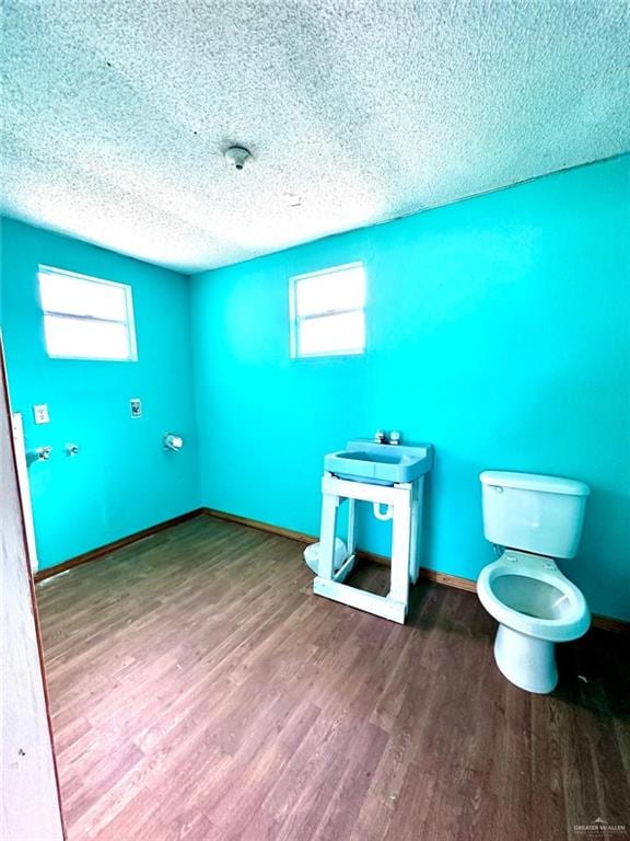 bathroom featuring wood-type flooring, a textured ceiling, and toilet