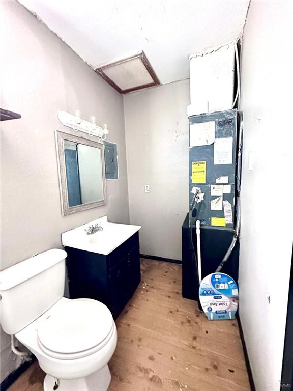 bathroom featuring hardwood / wood-style floors, vanity, electric panel, and toilet