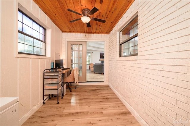 office with a wealth of natural light, ceiling fan, brick wall, and light wood-type flooring