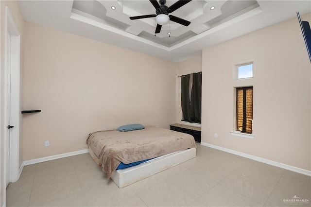 tiled bedroom with ceiling fan and a tray ceiling